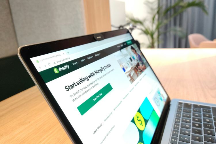 Shopify ecommerce platform visible in the MacBook Air on the wooden table