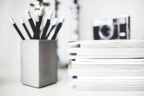 A bunch of pencil next to a stack of paper tablets