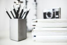 A bunch of pencil next to a stack of paper tablets