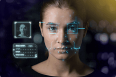 Woman looking at you and a computer screen