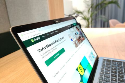 Shopify ecommerce platform visible in the MacBook Air on the wooden table