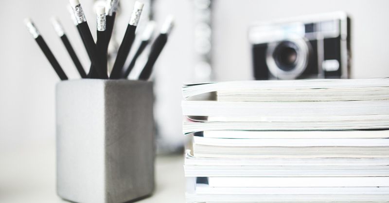 A bunch of pencil next to a stack of paper tablets